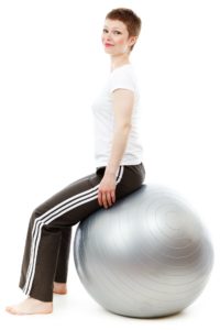 Femme assise sur un ballon de gymnastique, gardant un bassin mobile