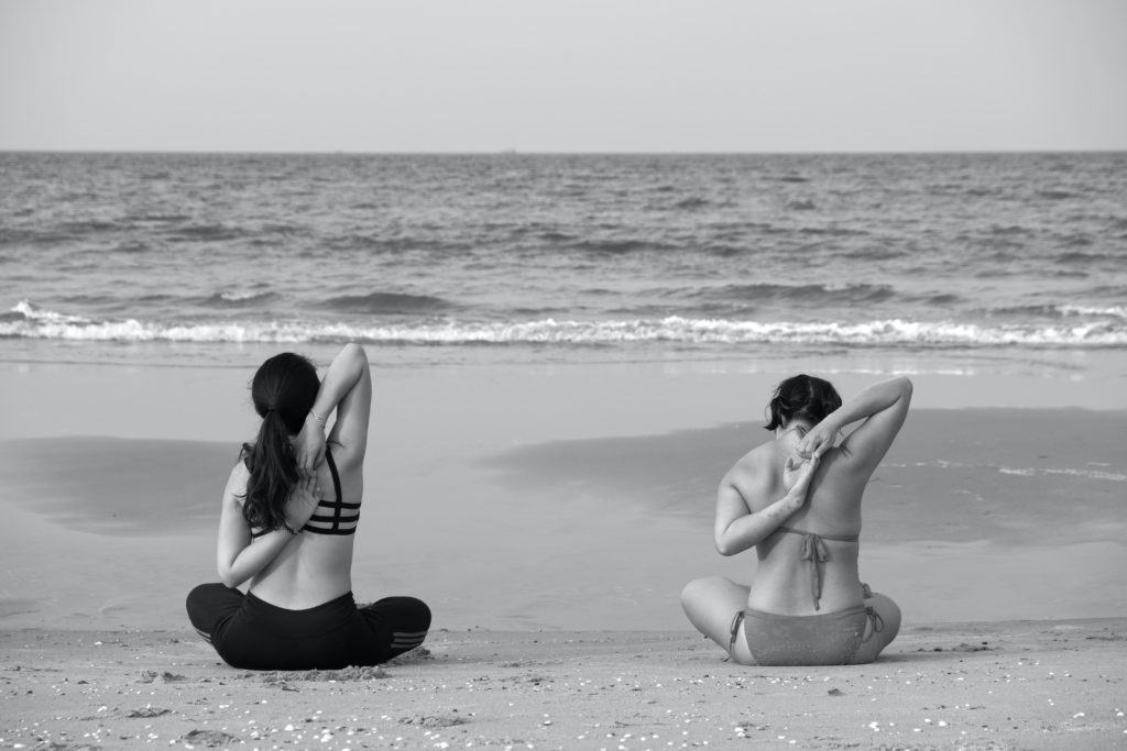 une femme force sur son épaule en pratiquant le yoga sur la plage. Peut-elle se blesser l'épaule?