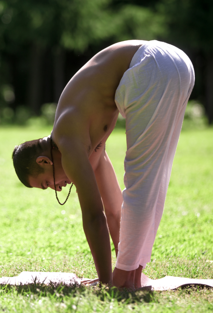 Pratiquant de yoga en pince debout, posture qui étire fortement l’arrière des cuisses et les ischio-jambiers.